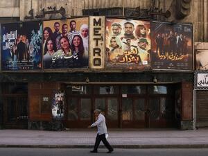 This picture taken early on May 24, 2020 shows a view of the historic Metro cinema theatre as a man walks past, along the commercial Talaat Harb street in the almost deserted city centre Egypt's capital Cairo, on the first day of Eid al-Fitr, the Muslim holiday which starts at the conclusion of the holy fasting month of Ramadan. Egypt had previously announced a lengthening of its night-time curfew and other measures to prevent large gatherings during the Eid al-Fitr holidays. One of the most important dates