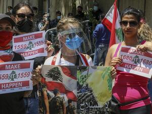Lebanese anti-government protesters wearing protective gear amid the COVID-19 pandemic lift placards demanding the implementation of United Nations resolutions including the disarmament of armed groups in the country, during a demonstration in the capital Beirut, on May 30, 2020. ANWAR AMRO / AFP