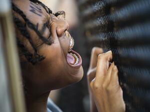 A woman shouts at a line of policemen standing near a metal fence recently erected in front of Lafayette Square near the White House to keep protestors at bay on June 2, 2020. Protesters returned to the area after they were tear gassed on June 1, 2020, to open the way for US President Donald Trump to walk to the church for a photo-op.  ROBERTO SCHMIDT / AFP