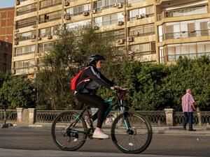 A woman cycles while wearing a face mask around her neck along the Nile riverfront in the Egyptian capital Cairo's southern district of Maadi on May 22, 2020, during the COVID-19 coronavirus pandemic. Khaled DESOUKI / AFP
