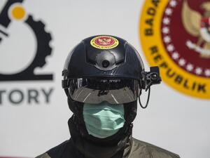 An official from Indonesia's state intelligence agency wears a helmet equipped to measure the body temperature of people at the venue of a rapid test for the COVID-19 coronavirus in Surabaya on June 4, 2020. Juni Kriswanto / AFP