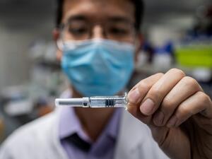 This file photo taken on April 29, 2020 shows an engineer displaying an experimental vaccine for the COVID-19 coronavirus that was tested at the Quality Control Laboratory at the Sinovac Biotech facilities in Beijing. China has mobilised its army and fast-tracked tests in the global race to find a coronavirus vaccine, and is involved in several of the dozen or so international clinical trials currently under way. NICOLAS ASFOURI / AFP