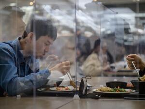 In this file photo taken on April 9, 2020 employees sit behind protective screens as part of preventative measures against the COVID-19 novel coronavirus, as they eat in a cafeteria at the offices of Hyundai Card credit card company in Seoul. Ed JONES / AFP