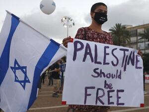 A protester, wearing a protective mask due to the COVID-19 pandemic, holds placards during a demonstration in Tel Aviv's Rabin Square to denounce Israel's plan to annex parts of the occupied West Bank, on June 23, 2020. Only a week before Prime Minister Benjamin Netanyahu intends to kick-start annexation plans in the occupied West Bank, Israel's premier is facing challenges at home and abroad. JACK GUEZ / AFP