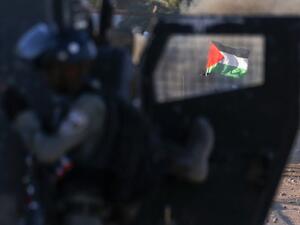 The Palestinian national flag is seen through the window of an Israeli military vehicle amid clashes following a rally against Israel's West Bank annexation plans, in the Jordan Valley village of Fasayil on June 24, 2020. JAAFAR ASHTIYEH / AFP