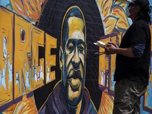A group of artists paint a mural of George Floyd on the wall outside of Cup Foods, where Floyd was killed in police custody, on May 28, 2020 in Minneapolis, Minnesota. People have gathered at the site since Floyd was killed earlier this week. Stephen Maturen/Getty Images/AFP Stephen Maturen / GETTY IMAGES NORTH AMERICA / Getty Images via AFP