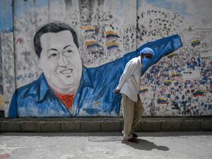 A man wearing a protective mask walks past a mural depicting Venezuela's late president (1999-2013) Hugo Chavez at the Perez de Leon Hospital of the Petare neighbourhood, in eastern Caracas on June 23, 2020, amid the new coronavirus pandemic. In Petare, the largest slum in Venezuela, more than 100 professionals of Doctors Without Borders face the COVID-19 pandemic getting around the crisis in the country's public healthcare sector. Federico PARRA / AFP