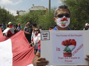 Lebanese anti-government protesters carry a large national flag and placards during a demonstration near the presidential palace in Baabda, east of Beirut, on June 25, 2020. ANWAR AMRO / AFP