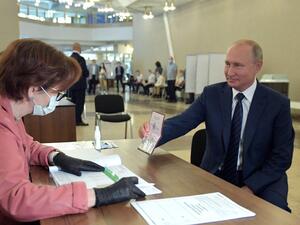 Russian President Vladimir Putin shows his passport to a member of a local electoral commission as he arrives to cast his ballot in a nationwide vote on constitutional reforms at a polling station in Moscow on July 1, 2020. Alexey DRUZHININ / SPUTNIK / AFP