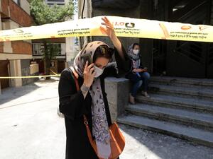 A mask-clad Iranian woman walks past the security cordon at the site of an explosion at the Sina At'har health centre in the upmarket northern neighbourhood of Tajrish in the capital Tehran on July 1, 2020. Iranian police questioned four people as part of investigations into a powerful explosion that killed 19 people at a Tehran clinic the night before, state media reported. ATTA KENARE / AFP