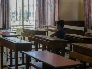 A Lebanese pupil looks out of the window as he sits in his empty classroom after coming to collect the books he left before the COVID-19 lockdown, at Our Lady of Lourdes school in the Lebanese city of Zahle, in the central Bekaa region, on June 30, 2020. (AFP)