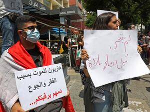 A demonstrator carries a placard (R) which reads in Arabic " He did not commit suicide, he was killed in cold blood" as they gather to denounce the death of a 61-year-old man, who committed suicide due to the country's deepening economic downturn, in the capital Beirut's Hamra street on July 3, 2020. ANWAR AMRO / AFP