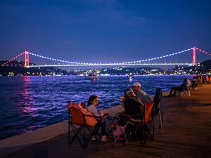 People enjoy the evening as they sit next to the shore of the Bosphorus as Fatih Sultan Mehmet bridge is seen in the backround on July 6, 2020 in Istanbul. Ozan KOSE / AFP