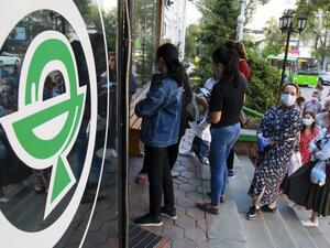 In this file photo taken on June 29, 2020 People wearing face masks stand in a line outside a pharmacy in Almaty. Ruslan PRYANIKOV / AFP