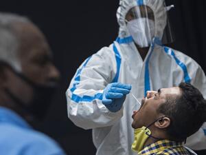 A health official wearing a Personal Protective Equipment (PPE) suit collects a swab sample from a man to test for the COVID-19 coronavirus at a temporary testing facility after authorities eased restrictions imposed as a preventive measure against the spread of the COVID-19 coronavirus, in New Delhi on July 8, 2020. (XAVIER GALIANA / AFP)