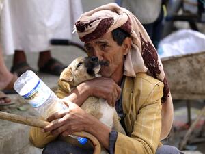 A Yemeni man plays with a puppy in a street in the capital Sanaa, on July, 13, 2020. MOHAMMED HUWAIS / AFP