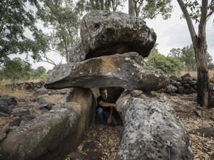 Uri Berger, a regional archaeologist for the Israel Antiquities Authority, sits inside a dolmen from the intermediate Bronze age, in the Israeli-annexed Golan Heights on July 13, 2020. This megalithic structure is one of the thousands of dolmens scattered around northern Israel and the region, burial tombs erected some 4000-4500 years ago in the Intermediate Bronze Era. MENAHEM KAHANA / AFP