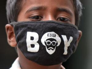 A boy wearing a facemask as a preventive measure against the spread of the COVID-19 coronavirus, looks on near a paddy field in Medak district of Telangana state on July 15, 2020. India joins a raft of countries and cities across the globe to reimpose localised lockdowns and other restrictions in the face of new outbreaks of the disease. Noah SEELAM / AFP