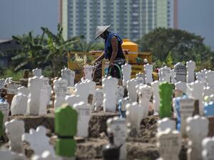 A worker pours water on newly planted flowers at a burial site for victims of the COVID-19 coronavirus at Keputih cemetery in Surabaya, East Java on July 15, 2020. JUNI KRISWANTO / AFP