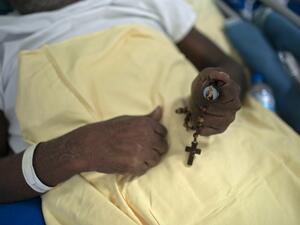 A COVID-19 patient holds a rosary at the post-COVID-19 ward of the Pedro Ernesto University Hospital (HUPE) in Rio de Janeiro, Brazil, on July 15, 2020, amid the novel coronavirus pandemic. The ward treats patients facing economic and social lacks that affect their capacity to keep proper medical care of their several health complications caused by COVID-19 and other diseases. Mauro PIMENTEL / AFP