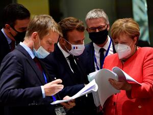 Spain's Prime Minister Pedro Sanchez (L), French President Emmanuel Macron (C) and German Chancellor Angela Merkel (R) look into documents during an EU summit in Brussels on July 20, 2020, as the leaders of the European Union hold their first face-to-face summit over a post-virus economic rescue plan. JOHN THYS / POOL / AFP