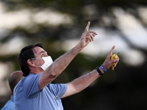 Brazilian President Jair Bolsonaro gestures as he speaks to supporters while holding a banana in his hand in the garden of the Alvorada Palace in Brasilia, on July 24, 2020. EVARISTO SA / AFP