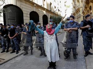 An elderly woman raises her arms in front of Lebanese security forces standing guard in front of the World Bank offices in the downtown district of the Lebanese capital Beirut on July 25, 2020. ANWAR AMRO / AFP