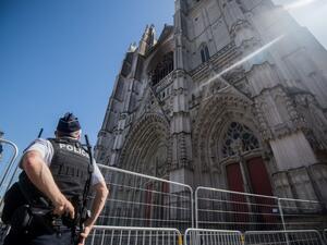 In this file photo taken on July 20, 2020 a police officer stands in front of the partially burnt facade of the Saint-Pierre-et-Saint-Paul Cathedral in Nantes, western France. Loic VENANCE / AFP