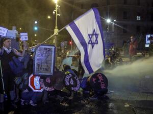 Protesters crouch down as police use water cannons as they clash during demonstrations against the Israeli government near the Prime Minister's residence in Jerusalem on July 25, 2020. AHMAD GHARABLI / AFP