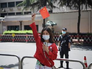 A woman waves a Chinese flag in front of the US consulate in Chengdu, southwestern China's Sichuan province on July 26, 2020. Tensions have soared between the two powers on a range of fronts including trade, China's handling of the novel coronavirus and a tough new security law for Hong Kong, with US officials this week warning of a "new tyranny" from China. Noel Celis / AFP