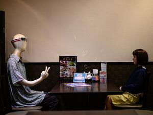 Mannequins, one clad in a face shield and another depicting a child and used as a method to maintain social distancing among diners, are seen seated in a restaurant in the Akabane district of Tokyo on July 26, 2020, amid the COVID-19 coronavirus pandemic. Philip FONG / AFP