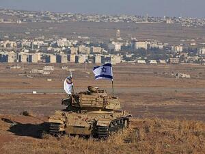 An Israeli flag flutters above the wreckage of a tank on a hill in the Golan Heights overlooking the border with Syria on October 18, 2017. (AFP Photo/Jalaa Marey)