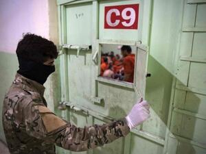 A member of the Syrian Democratic Forces guards IS suspects in north-east Syria. (AFP/GETTY IMAGES)