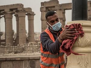 A municipality worker cleans lamp posts amid coronavirus fears outside the Luxor Temple, March 12, 2020. (AFP)