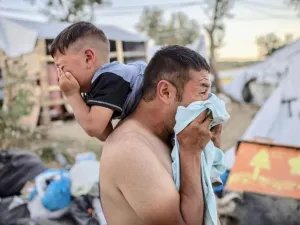 Man and boy cry after police fire tear gas during clashes at Moira refugee camp on the Greek island of Lesbos on Sunday (AFP)