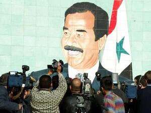 Foreign and local cameramen crowd in front of a mural of late Iraqi President Saddam Hussein in 2002. (AFP)