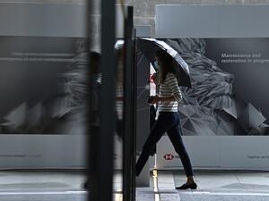 A woman walks past an HSBC lion graphic outside the local headquarters of the bank in Hong Kong on August 3, 2020. HSBC said on August 3, 2020 its first half post-tax profits for 2020 plunged 69 percent on year as the Asia-focused banking giant was hammered by the coronavirus and spiralling China-US tensions. Anthony WALLACE / AFP