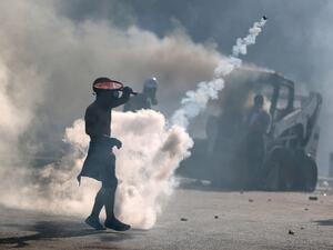A topless protester wearing a gas mask uses a tennis racket to volley back a tear gas canister during clashes with security forces in downtown Beirut on August 8, 2020, following a demonstration against a political leadership they blame for a monster explosion that killed more than 150 people and disfigured the capital Beirut. PATRICK BAZ / AFP