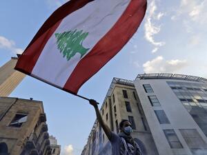 A Lebanese protester waves a national flag amid clashes with security forces in central Beirut on August 10, 2020. Lebanese Prime Minister Hassan Diab will announce his government's resignation imminently over the backlash from the deadly Beirut port explosion. JOSEPH EID / AFP