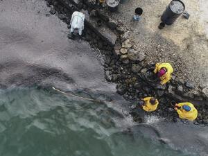 An aerial view shows people scooping leaked oil on August 10, 2020, from the MV Wakashio bulk carrier that had run aground at the beach in Bambous Virieux, southeast Mauritius. L'Express Maurice / AFP
