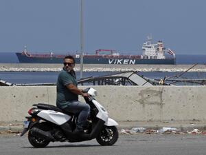 A motorcyclist rides across from the Kronviken crude oil tanker docked at the destroyed port of Beirut following a huge explosion that disfigured the Lebanese capital, on August 12, 2020. JOSEPH EID / AFP