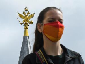 A woman wearing a face mask to protect against the coronavirus disease walks in front of a two-headed eagle, the national symbol of Russia, at the top a building on Red Square in downtown Moscow on August 12, 2020. Russia claimed on August 11 it has developed the world's first vaccine offering "sustainable immunity" against the coronavirus, despite mounting scepticism about its effectiveness as fears grow over a second wave of infections across the globe. Kirill KUDRYAVTSEV / AFP
