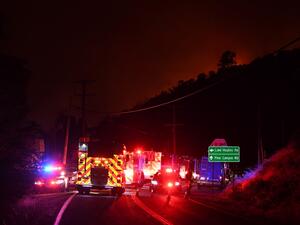 Fire trucks and emergency vehicles huddle on the road as the horizon is set ablaze by the Lake Fire flames in the Angeles National Forest, by Lake Hughes, 60 miles north of Los Angeles, California on August 12, 2020. Robyn Beck / AFP