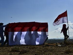 The youth of state defense carry Indonesian flags to commemorate 75th Indonesia's Independence Day which falls on August 17, at a mountain of garbage in Banda Aceh on August 16, 2020. CHAIDEER MAHYUDDIN / AFP
