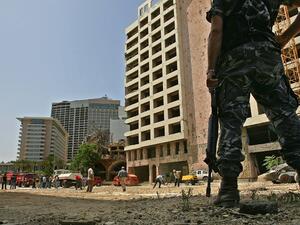 This file photo taken on May 31, 2007 shows a Lebanese policeman securing the site as municipality employees work on closing a crater at the site where a massive car bomb explosion killed former prime minister Rafiq Hariri in Beirut on February 14, 2005. The special tribunal trying the four suspects accused of the 2005 assassination of Lebanon's former prime minister Rafic Hariri is expected to deliver its verdict on on August 18, 2020.  MARWAN NAAMANI / AFP