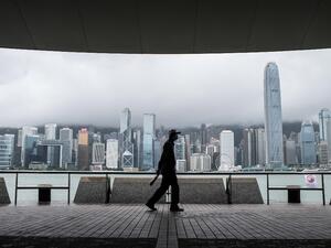 A man walks on Kowloon's Tsim Sha Tsui waterfront that faces Victoria Harbour and the Hong Kong Island skyline (back), after Typhoon Higos swept past overnight in Hong Kong on August 19, 2020. Anthony WALLACE / AFP