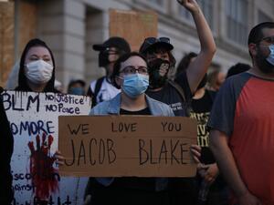 People hold signs as they march outside the County Courthouse during demonstrations against the shooting of Jacob Blake in Kenosha, Wisconsin on August 25, 2020. KAMIL KRZACZYNSKI / AFP