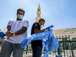 Workers suit up in PPE (personal protective equipment) before sterilizing a mosque in Jordan's capital Amman on June 3, 2020. (AFP)