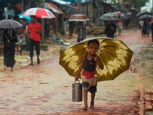 A Rohingya refugee boy shelters under an umbrella as he makes his way during a monsoon rainfall at Kutupalong refugee camp in Ukhia on Sept. 12, 2019. (AFP Photo)