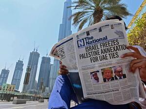 A man reads a copy of UAE-based The National newspaper near the Burj Khalifa, in the gulf emirate of Dubai on August 14. (AFP)